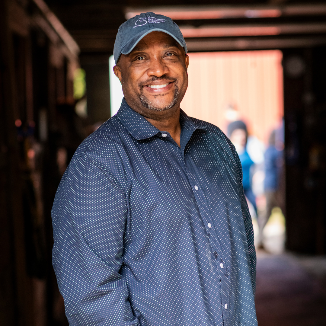 Torin Moore, Board Member of the Therapeutic Equestrian Center smiling in the barn.